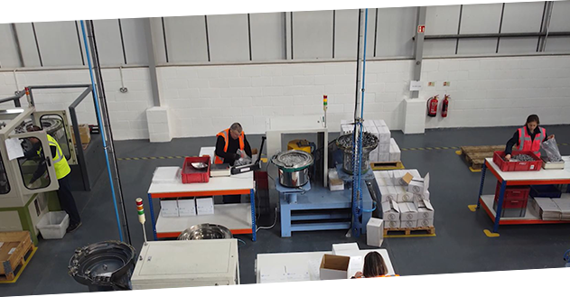 An image of three Powell Gee warehouse employees stood at their work stations, packaging product.