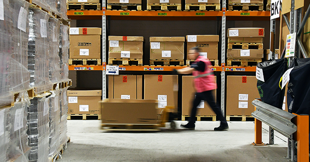 A man pushing a pallet along a corridor of a warehouse